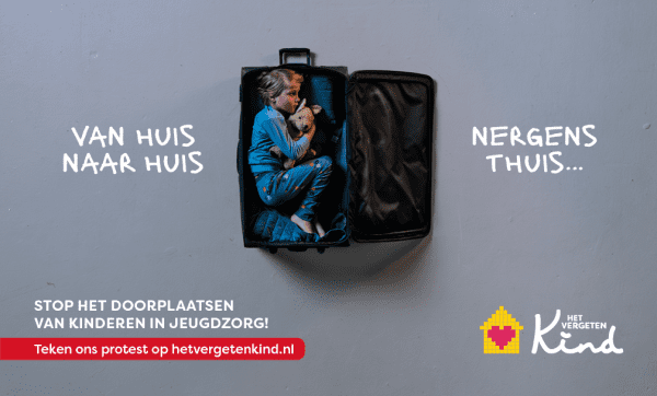 Een campagnebeeld voor 'Het Vergeten Kind'. Centraal in de afbeelding zit een jong kind in een open koffer op de vloer. Het kind draagt een pyjama en houdt een knuffel vast. Links van de koffer staat in grote letters 'VAN HUIS NAAR HUIS' en rechts 'NERGENS THUIS...'. Onderaan de afbeelding staat 'STOP HET DOORPLAATSEN VAN KINDEREN IN JEUGDZORG!' en 'Teken ons protest op hetvergetenkind.nl'. In de rechteronderhoek staat het logo van Het Vergeten Kind.